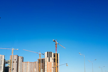 construction cranes and buildings against the blue sky