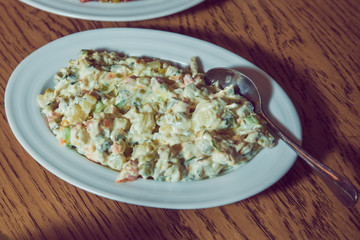 On the plate capital salad.Mayonnaise salad. Food background - salad olivier close-up. Green peas, cucumber, potatoes, sausage, mayonnaise . Azerbaijani capital salad.