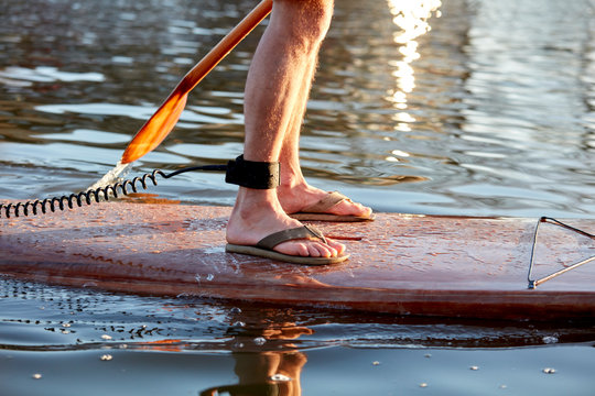 Close Up View Of Legs Of Man Standing On Paddleboard