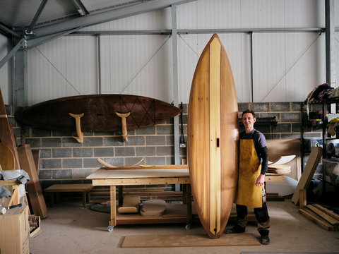 Portrait of man standing and smiling in paddleboard workshop