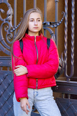 Cute teenager girl on a background of a city street in a bright jacket.