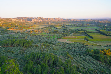 Sunset view of the Alpilles valley with green olive tree groves below the historic fortified village Les-Baux-de-Provence, in Bouches du Rhone, Provence, France.