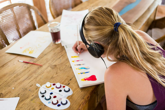 Girl wearing headphones and doing watercolor sketch