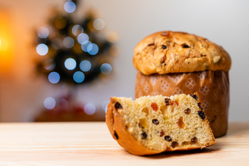 Delicious Panettone slice with candied fruits with blinking blurred christmas lights.