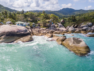 Aerial view of turquoise waves beating on stones. Thailand