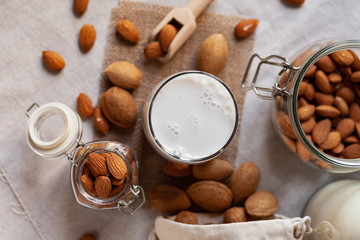 Fresh organic vegan almond milk. Alternative source of protein for vegetarians. Raw almonds, peeled and unpeeled to illustrate ingredients. Concept of healthy lifestyle. Closeup, top view, background