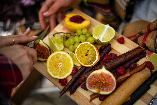 Young girl holding tklapi dried mashed fruit candy pastille pulp. Colorful leather from apricot, kiwi, dogwood, strawberry. Cuisine roll up snack. Grapes, dates, lemon, orange, raspberries. Board.