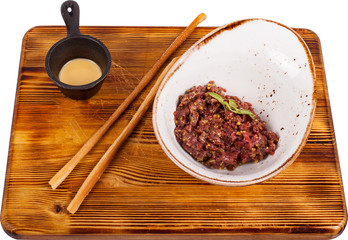 Beef tartare served with smoked yolk sauce and traditional grissini bread sticks on wooden board.
