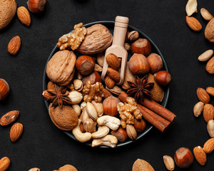 Different nuts and spices. Natural organic products for healthy lifestyle. Vegetarian food concept.  Raw almond, cachou, walnut, hazelnut, pistachio. Black background, closeup, copy space for text