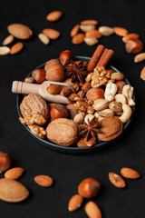 ifferent kinds on nuts and spices. Natural organic products for healthy lifestyle. Vegetarian food concept.  Raw almond, cachou, walnut, hazelnut, pistachio. Black background, closeup
