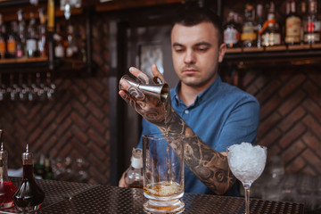 Professional bartender preparing a drink. Handsome male barman mixing liquor