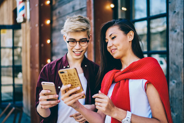 Positive smiling asian hipster guys using bluetooth connection for sharing multimedia files on...