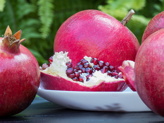 Ripe pomegranates  on dark wooden table and green background.