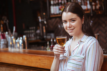 Young beautiful woman smiling, having a drink at the bar, copy space