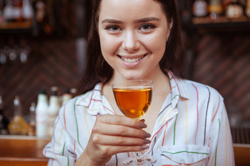 Close up of a happy young woman enjoying cocktail at the bar. Relax, lifestyle, celebration concept