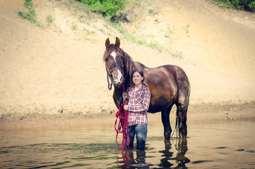 portrait of girl and red trakehner stallion horse in the river in the summer