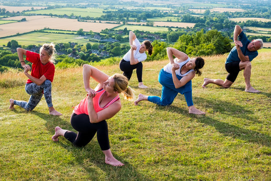 People performing yoga on hill