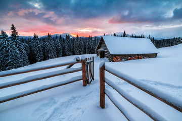 wooden cabin in winter mountains on sunset
