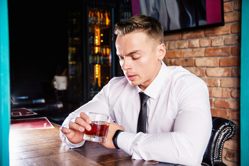 Businessman drinks whiskey at the bar