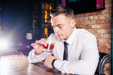 Businessman drinks whiskey at the bar