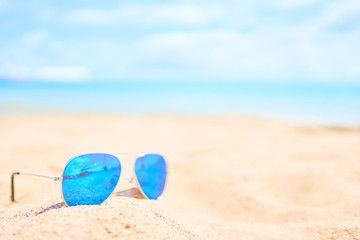 Sunglasses on the beach with ocean and sky on background
