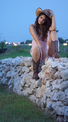 Beautiful woman sitting on a fence of rocks staring off into the camera