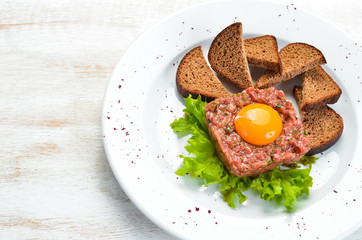 Veal tartar with egg yolk and black bread. Top view. Free space for your text.