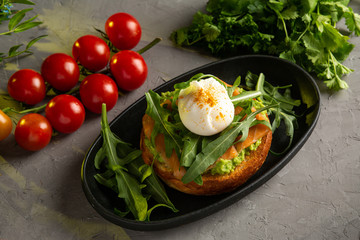 bruschetta salmon with avocado - salted salmon with guacamole, arugula and poached egg on a warm fried bun