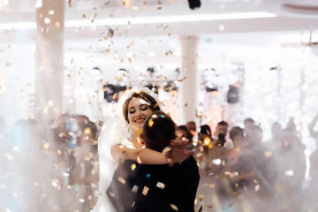 Obraz na płótnie Canvas Handsome wedding dance with confetti. Gorgeous stylish happy bride and groom performing their emotional first dance, wedding in a restaurant. Creative couple dancing their first dance