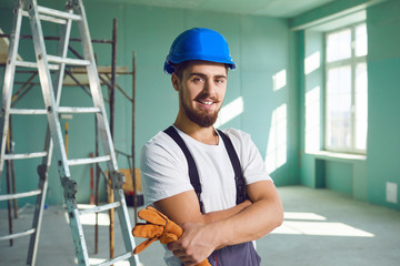 Builder contractor bearded man in helmet smiling while standing at a construction site.