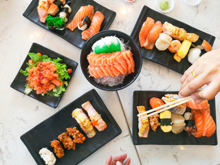 Top view of japanese traditional food A set of sushi rolls on a table in a restaurant , hand of people eating sushi rolls using bamboo sticks.