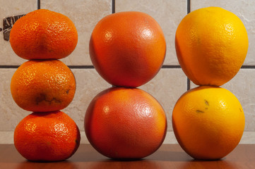 three tangerines, two grapefruits and two aprons - autumn kitchen pyramidal still life on a background of a wall lined with beige tiles