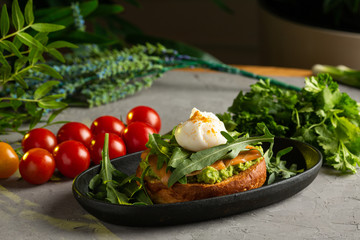 bruschetta salmon with avocado - salted salmon with guacamole, arugula and poached egg on a warm fried bun