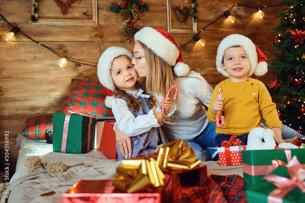 Wall mural Mother and children with gifts in the house for Christmas