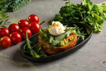 bruschetta salmon with avocado - salted salmon with guacamole, arugula and poached egg on a warm fried bun