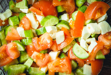 Salad with watermelon, feta, arugula and basil leaves on plate, on wooden background