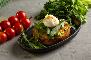 bruschetta salmon with avocado - salted salmon with guacamole, arugula and poached egg on a warm fried bun