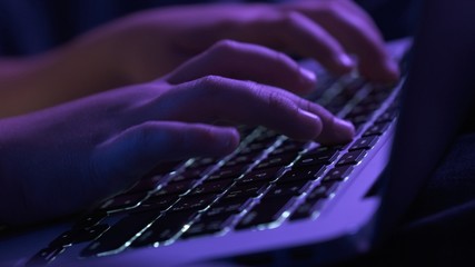 Child typing text message on keyboard. Close up view children's fingers typing text on keyboard. Caucasian kid holds notebook and types text.  Evening time..