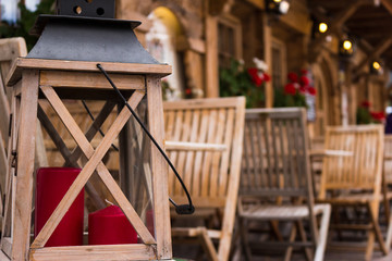 lantern with christmas candle and wooden chairs in the background and mountain cabin
