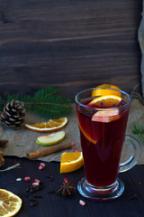 hot drinks of winter and autumn. mulled wine with slices of orange, apple and spices, cinnamon and anise star on a wooden table with winter decorations. vertical
