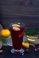 mulled wine with slices of orange, apple and spices, cinnamon and anise star on a wooden background with winter decorations. hot drinks of winter and autumn. vertical