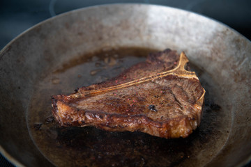 Delicious Simply Cooked T-bone steak on Stainless Steel Skillet
