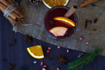 Fototapeta na wymiar hot mulled wine with slices of orange, apple and spices, cinnamon and anise star on a wooden background with winter decorations. hot drinks of winter and autumn. top view. copy space