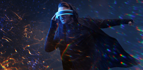 Young man having virtual reality experience. Guy using VR helmet. Augmented reality, future technology, game concept. Rainbow light, fire flares.