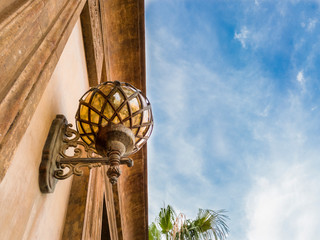 a vintage lamp on the gate of palace and blue sky in the background
