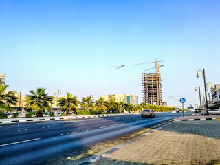 less traffic flow in a modern city in the morning with beautiful sunshine and palm trees in the middle on the road