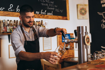 man pouring beer from tap in cafe