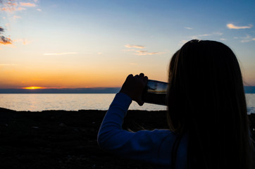 Obraz premium Kid girl takig a photo of the sunset on the beach with a smartphone