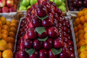 Lots of fruits on the fruit market counter. Pile of ripe red apples in pyramid shape.