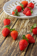 Strawberries on a decorated plate and over a wooden table